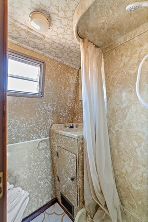 A bathroom with a marble wall, a window, a sink, and a shower curtain. - Vintage Resort Stay | Magic Lamp | Cañon City, CO (Canon City)