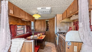 A compact RV interior with a dining area, kitchenette, and a ceiling fan.