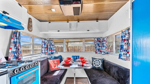 A compact RV interior with a kitchenette, seating area, and large windows. - Vintage Motorhome Retreat | Unique Stay in Cañon City (Canon City)
