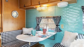 A compact kitchenette with wooden cabinets, a small table, and checkered seating.