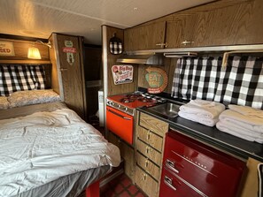 A compact kitchen with a stove, sink, and storage cabinets. - Vintage Trailer Stay | 1 Unit | Near Ruby's Diner in Cañon City (Canon City)