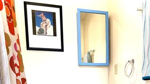 Ein Badezimmer mit Toilette in Blau, einem Waschbecken, einem Schrank, einem Spiegel und einer Duschvorhang.