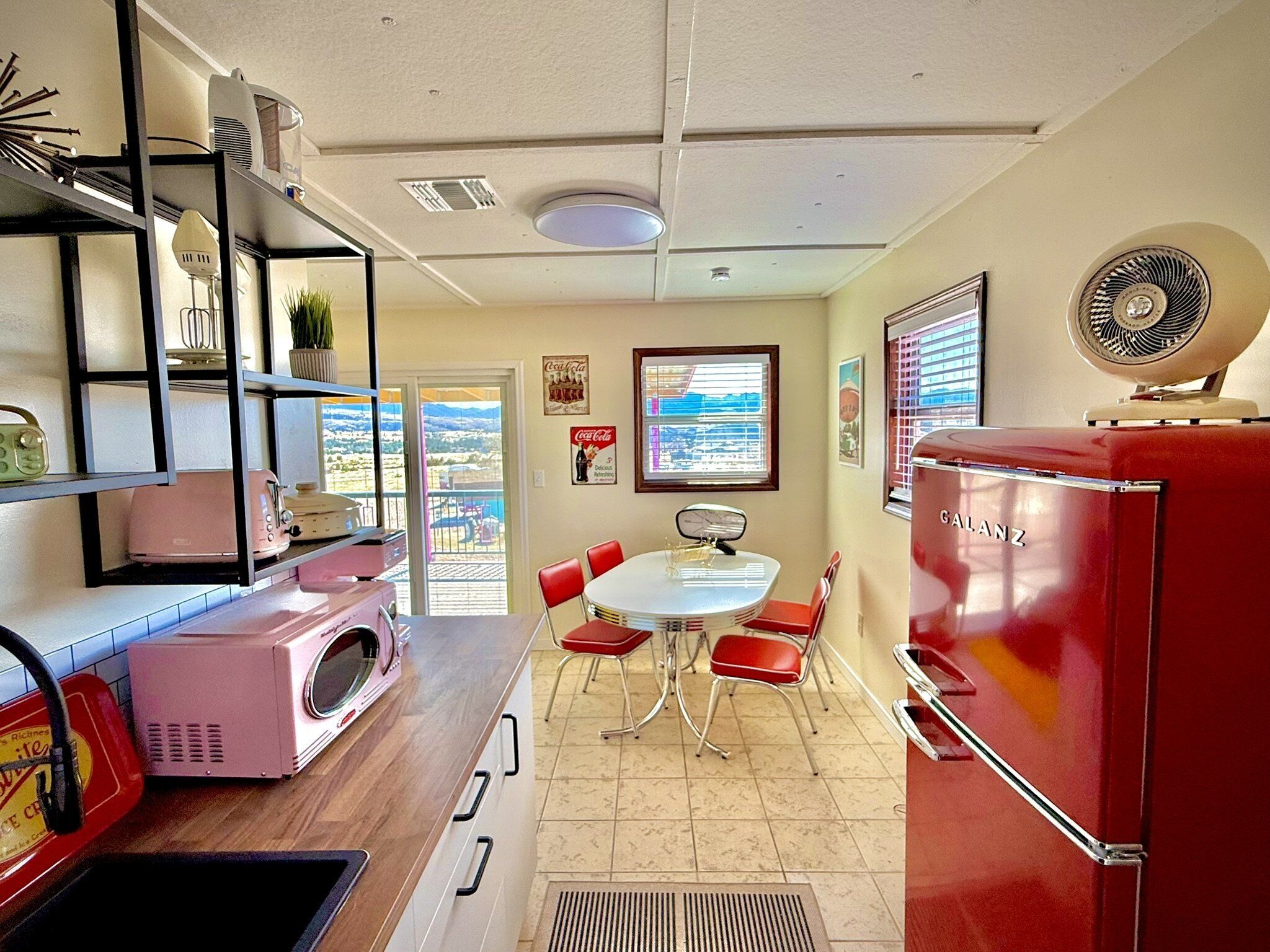 Una cocina con un refrigerador rojo, una lavadora y un comedor con una mesa y sillas.