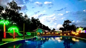 Ein Schwimmbecken mit Rutsche und leuchtenden Palmen-Dekorationen.