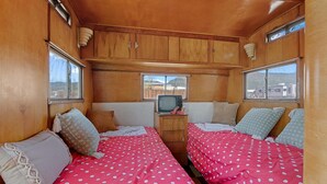 Ein kompaktes Wohnmobil-Interieur mit zwei Betten, einem kleinen Fernseher und Holzwänden.