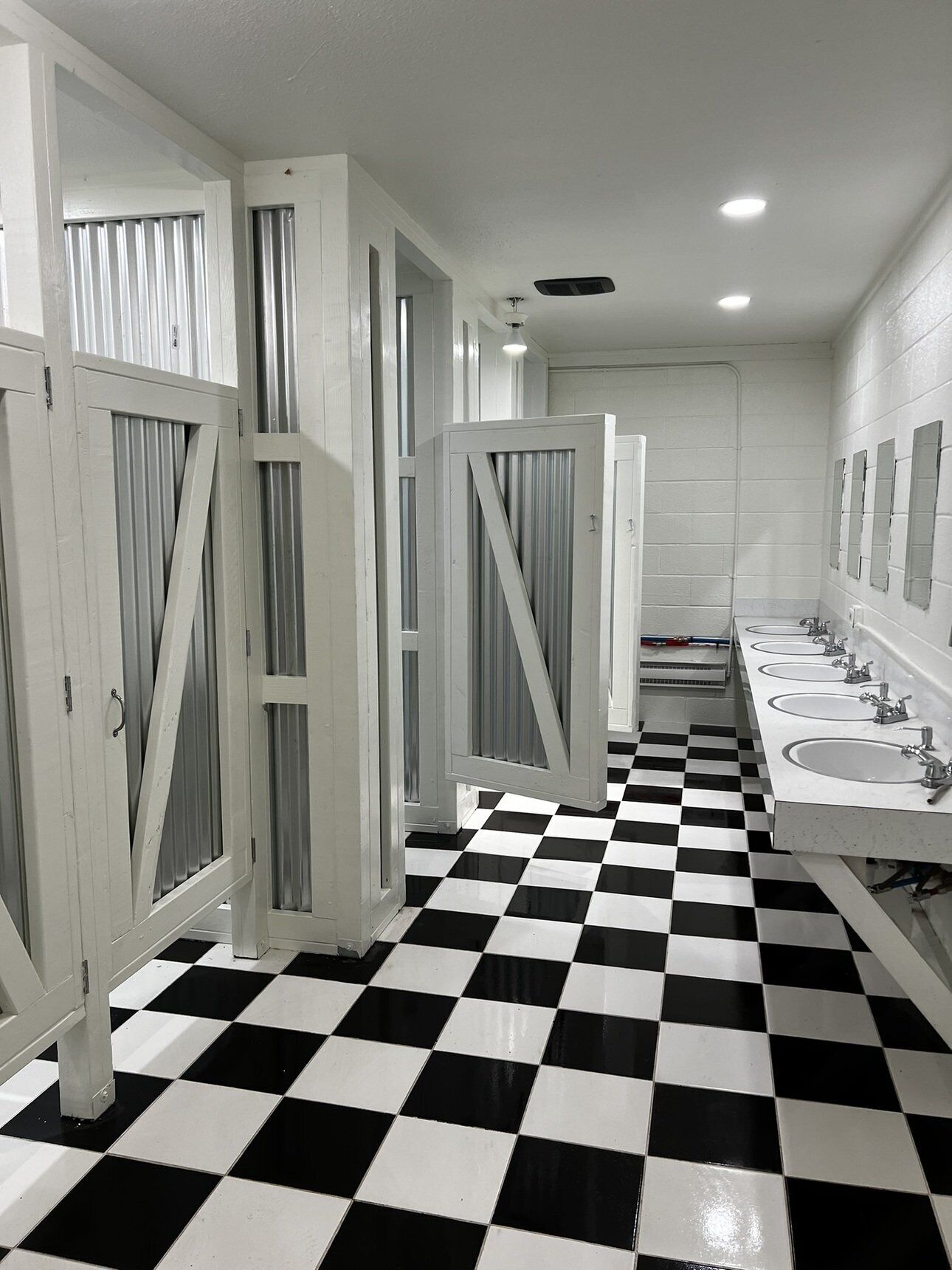 A public restroom with a black and white checkered floor, white walls, and multiple sinks.