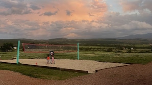 A volleyball court with a net, surrounded by a grassy field and hills in the background. - Vintage Tiki Motorhome | Unique Stay in Cañon City, CO (Canon City)
