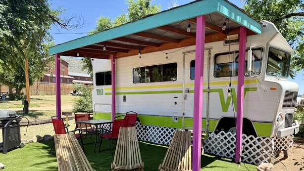 A recreational vehicle with a covered patio area, outdoor seating, and a grill. - Vintage Tiki Motorhome | Unique Stay in Cañon City, CO (Canon City)