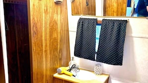 Ein kleines Badezimmer mit Holzsärchen, einem Waschbecken, einer Toilette und einem Spiegel.