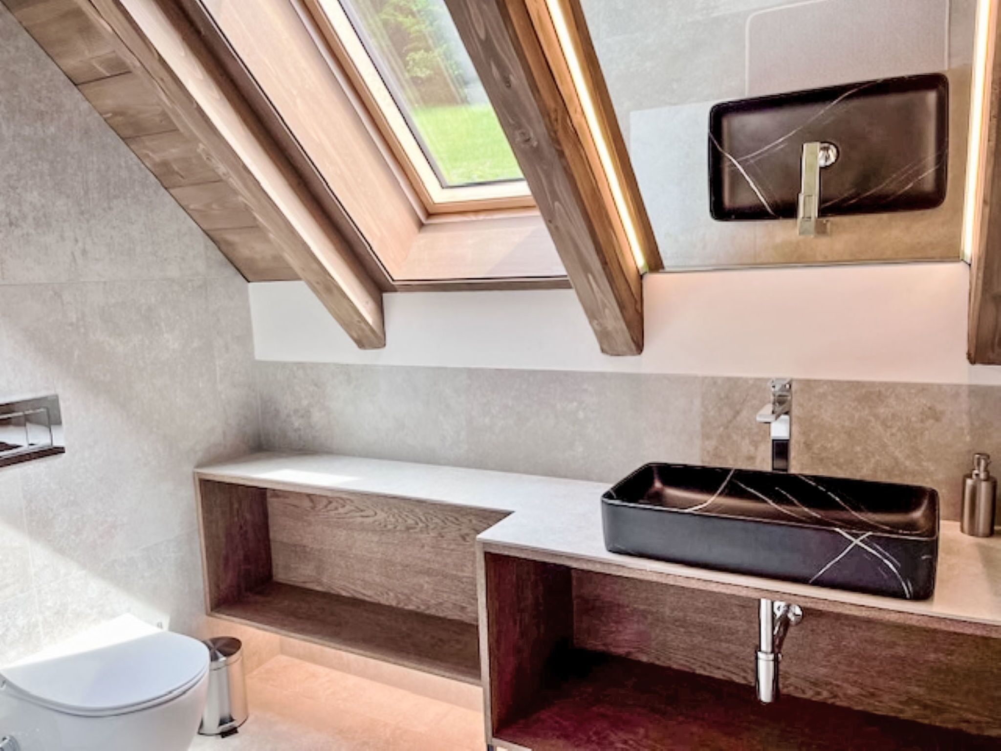 A modern bathroom with a skylight, a built-in sink, and a vanity with a mirror.