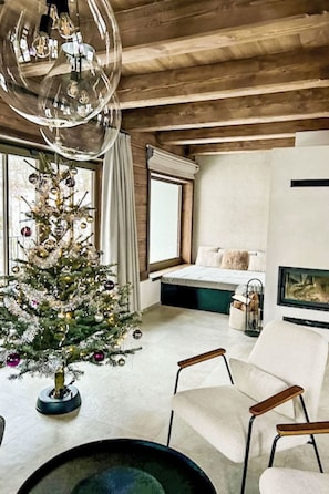 A modern living room with a Christmas tree, a large chandelier, a bed, and a dining area. - Pod hvězdami by Interhome (Strážné)