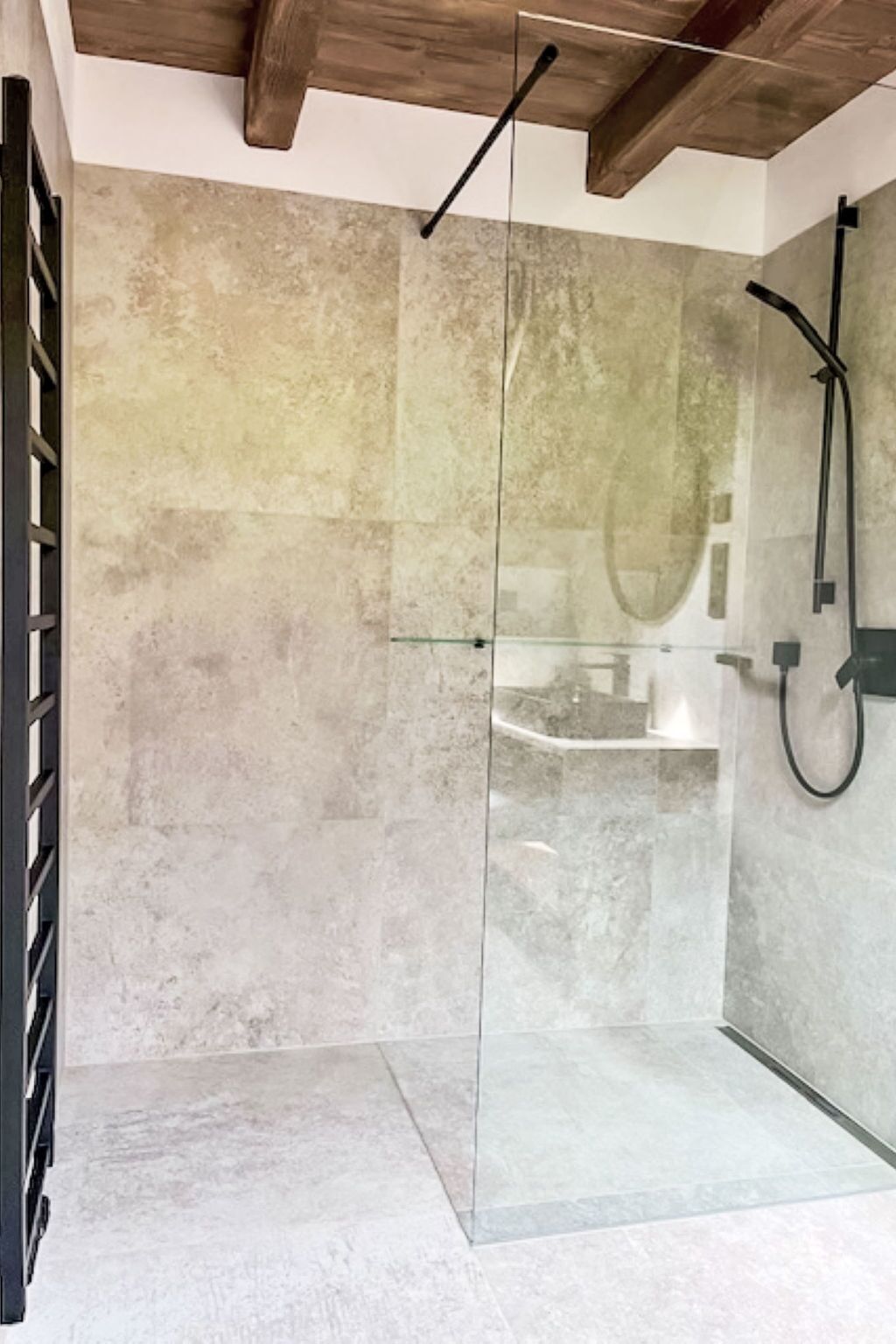 A modern bathroom with a glass shower enclosure, a wooden ceiling, and a visible sink area.