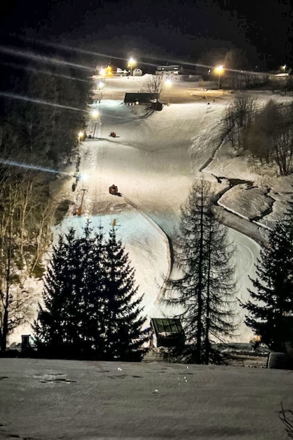Pista de esquí nevada de noche con iluminación artificial.