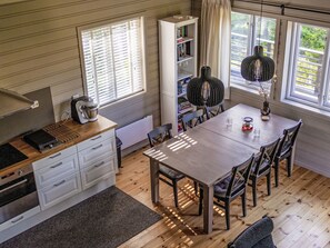 Et kompakt køkken med spiseplads, en reol og et vindue med persienner.