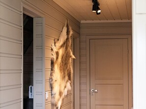 Et rum med en dør, en lysarmatur og en pelsfrakke hængende på væggen.