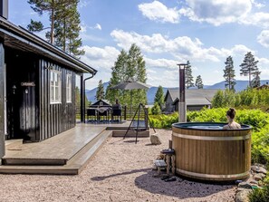 Une cabane en bois avec une terrasse, un jacuzzi et une vue sur les montagnes.