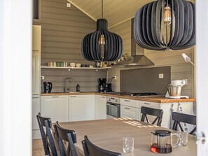 A modern kitchen with white cabinets, a wooden countertop, and a dining table with chairs. There are two pendant lights hanging above the counter. - Vacation home Vrådal by Interhome (Vrådal)