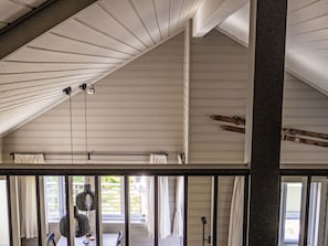 A room with a sloped ceiling, large windows, and a view of greenery outside.
