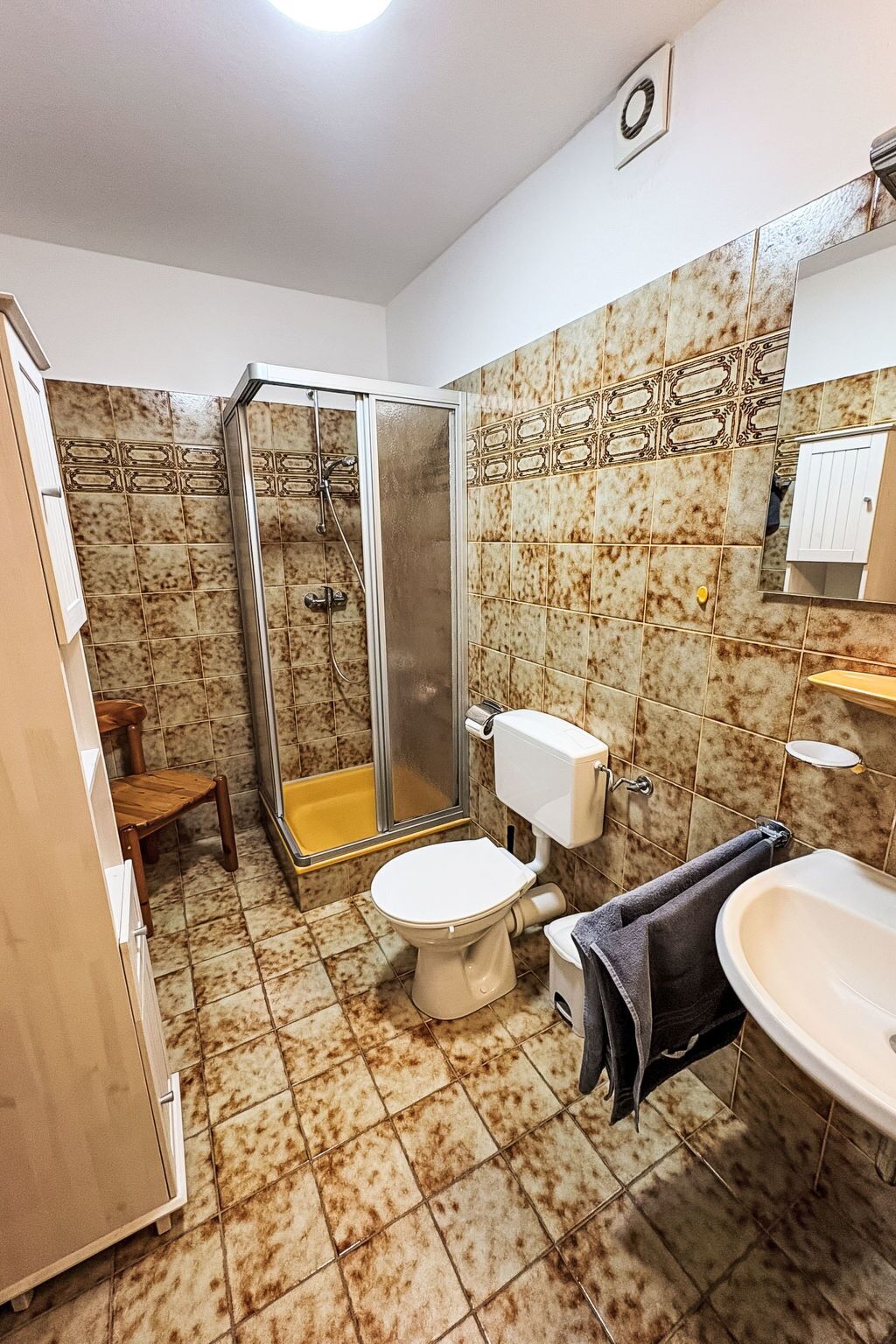 A bathroom with a shower, toilet, sink, and a mirror.