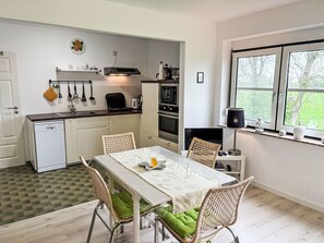 A compact kitchen with a dining area, a built-in oven, and a window with a view. - Friesenwohnung by Interhome (Wangerland)