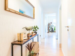 A hallway with a console table, a large mirror, and a Buddha statue. - 1OG "R" Helle 80m² 3-Zimmer Wohnung näh by Interhome (Freilassing)