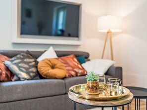 A modern living room with a grey sofa, decorative pillows, a round coffee table with a tray, a potted plant, and a floor lamp. - 1OG "R" Helle 80m² 3-Zimmer Wohnung näh by Interhome (Freilassing)