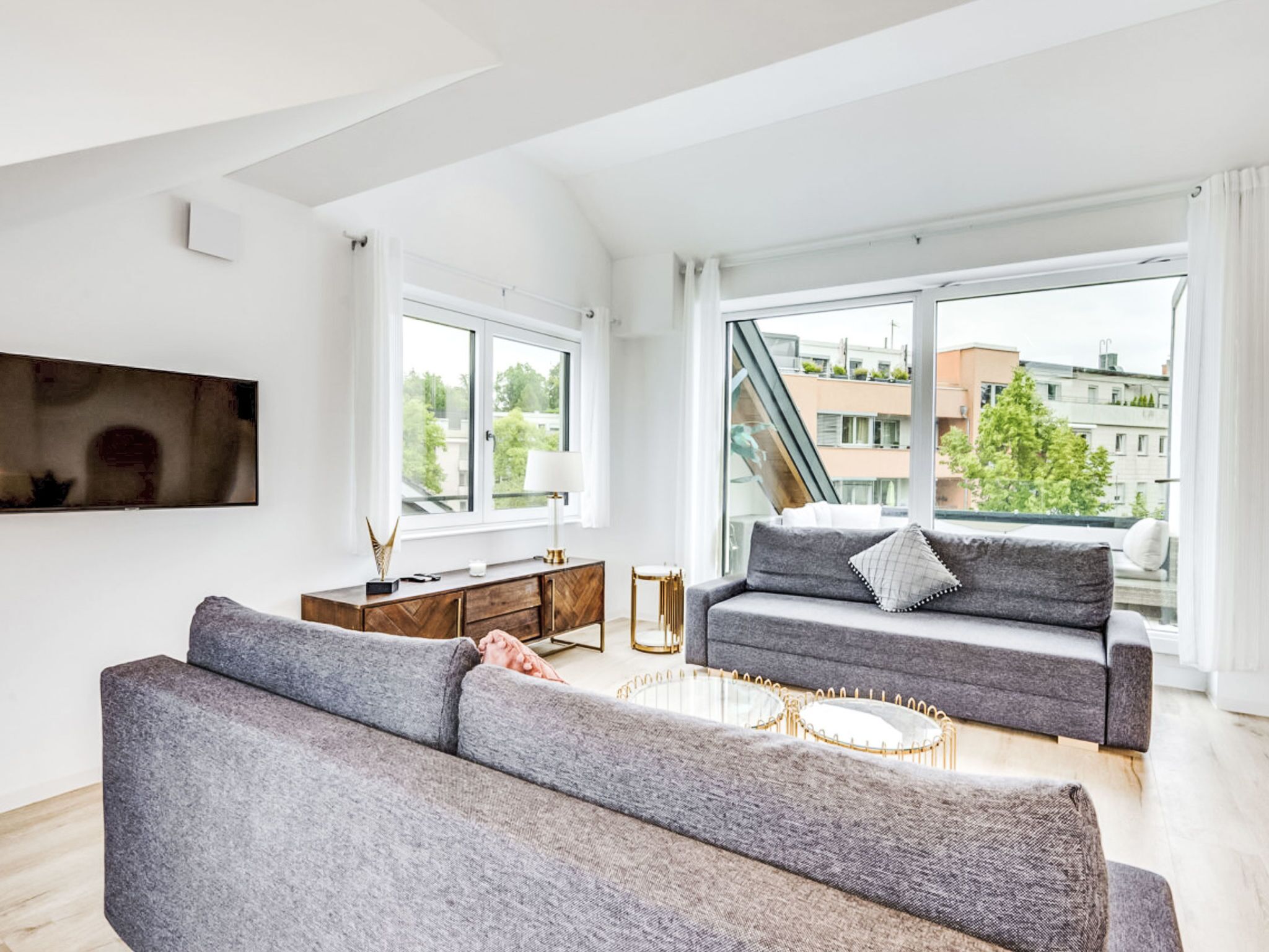 Ein modernes Wohnzimmer mit einer Couch, einem Couchtisch und einem an der Wand montierten Fernseher.