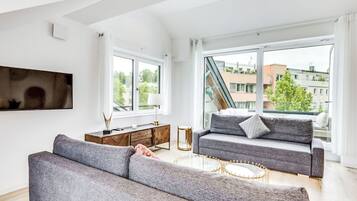 Ein modernes Wohnzimmer mit einer Couch, einem Couchtisch und einem an der Wand montierten Fernseher.