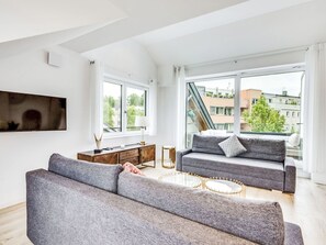 A modern living room with a sofa, a coffee table, and a TV mounted on the wall. - Luxus 80m² Dachgeschoss City Wohnung by Interhome (Munich)