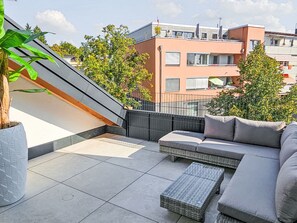 A rooftop terrace with a modern sofa, a small table, and a potted plant. - Luxus 80m² Dachgeschoss City Wohnung by Interhome (Munich)