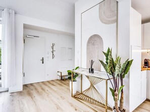 A modern interior with a white door, a wooden floor, a white table with a gold frame, and a large plant. - Luxus 80m² Dachgeschoss City Wohnung by Interhome (Munich)
