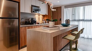 Een moderne keuken met een centraal kookeiland, roestvrijstalen apparatuur en een groot raam.