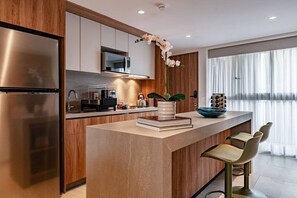 A modern kitchen with a central island, stainless steel appliances, and a large window. - Condesa Penthouse with Rooftop Terrace & BBQ (Mexico City)