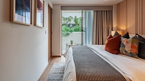 Een slaapkamer met een bed, uitzicht op groen en een deur naar een balkon.