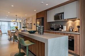 A modern kitchen with a central island, bar stools, a microwave, a refrigerator, and a gas stove. - Condesa Penthouse with Rooftop Terrace & BBQ (Mexico City)