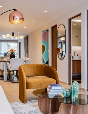 A modern living room with a sofa, a glass coffee table, and a dining area in the background. - Condesa Penthouse with Rooftop Terrace & BBQ (Mexico City)