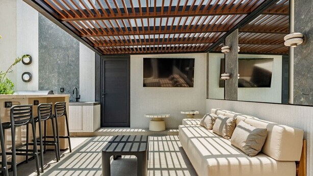 A modern outdoor living space with a wooden pergola, a sofa, a dining area with chairs, a small table, and a kitchen area with a sink and cabinets. - Condesa Apartment Near Parque México & Roma (Mexico City)