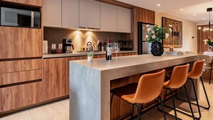 A modern kitchen with a central island, wooden cabinetry, and bar stools. - Condesa Apartment Near Parque México & Roma (Mexico City)
