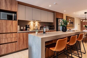 A modern kitchen with a central island, wooden cabinetry, and bar stools. - Condesa Apartment Near Parque México & Roma (Mexico City)