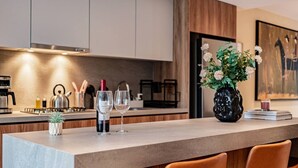 A modern kitchen with a marble countertop, wine glasses, a vase with flowers, and a painting on the wall. - Condesa Apartment Near Parque México & Roma (Mexico City)