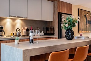 A modern kitchen with a marble countertop, wine glasses, a vase with flowers, and a painting on the wall. - Condesa Apartment Near Parque México & Roma (Mexico City)