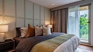 A bedroom with a bed, pillows, a nightstand, a lamp, and a view of greenery through a window. - Condesa Apartment Near Parque México & Roma (Mexico City)