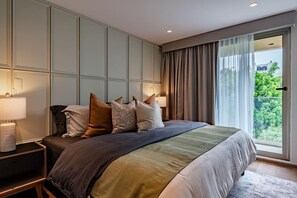 A bedroom with a bed, pillows, a nightstand, a lamp, and a view of greenery through a window. - Condesa Apartment Near Parque México & Roma (Mexico City)