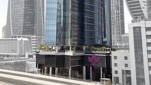 A modern high-rise building with a curved glass facade, surrounded by other tall structures. - Standard | Park Regis BB | Business Bay Base, Outdoor Pool, Spa Reset (Dubai)