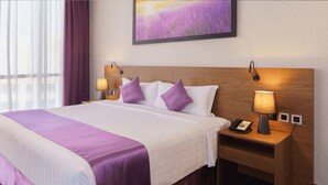 A hotel room with a large bed, two bedside lamps, a nightstand with a phone, and a painting on the wall. - Standard | Park Regis BB | Business Bay Base, Outdoor Pool, Spa Reset (Dubai)