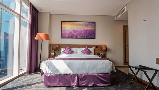 A hotel room with a large bed, a window with curtains, a wall-mounted painting, and a lamp. - Standard | Park Regis BB | Business Bay Base, Outdoor Pool, Spa Reset (Dubai)
