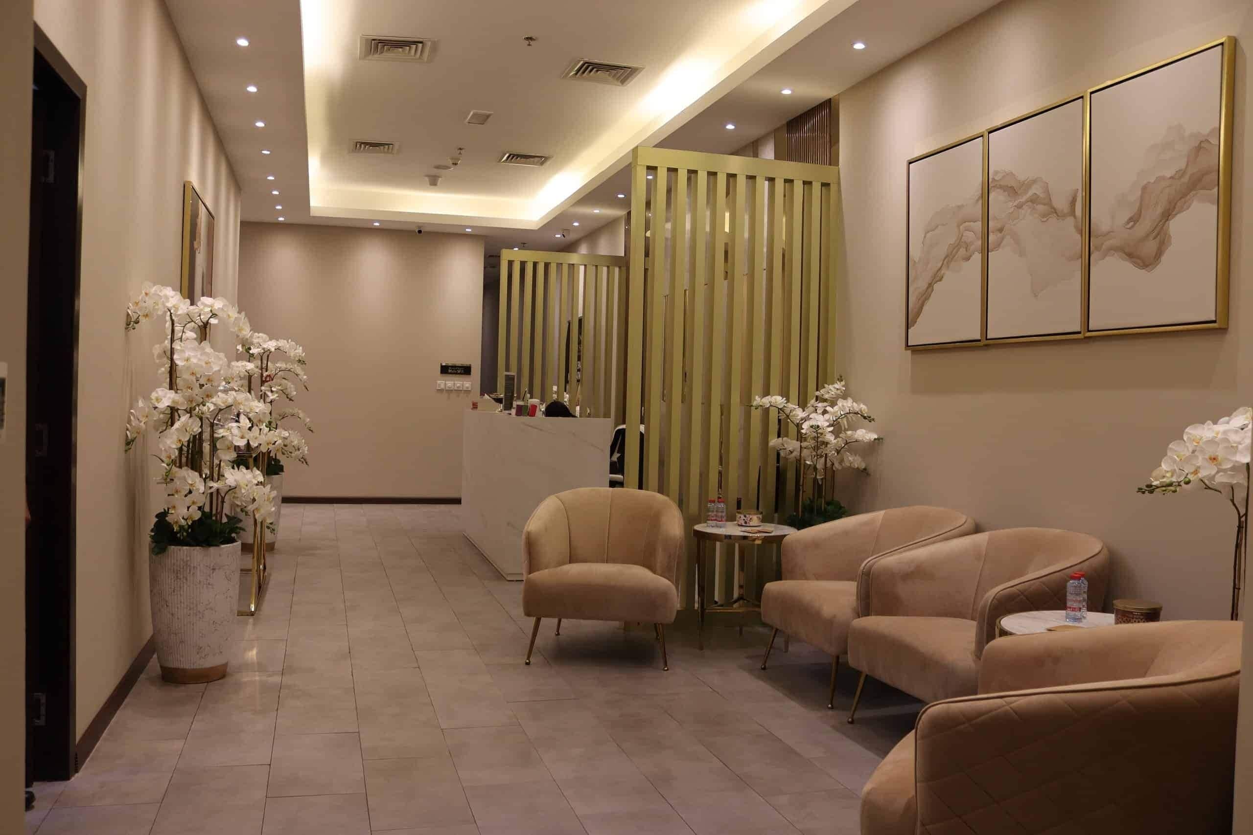 Un hall d’hôtel comprenant un comptoir d’accueil, un espace salon et des éléments décoratifs tels que des orchidées et des œuvres d’art.