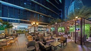 An outdoor lounge area with seating, a pergola, and a view of a modern building.
