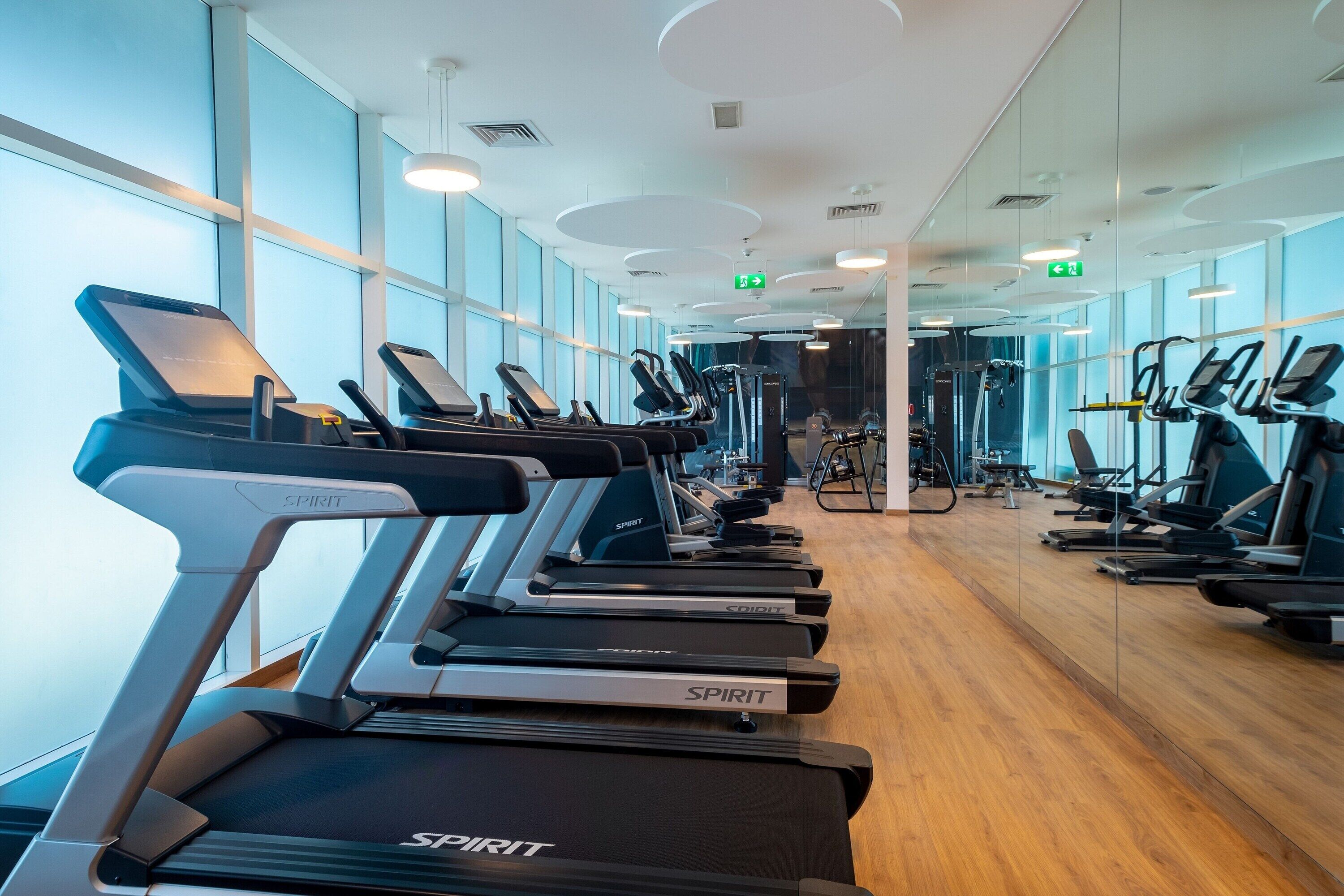 Een fitnessruimte met loopbanden, spiegels en trainingsapparatuur.