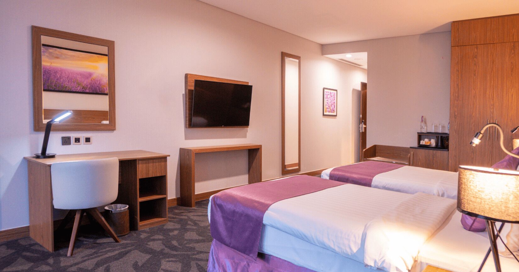 Habitació d'hotel amb dos llits, una taula de nit, una televisió i un armari.